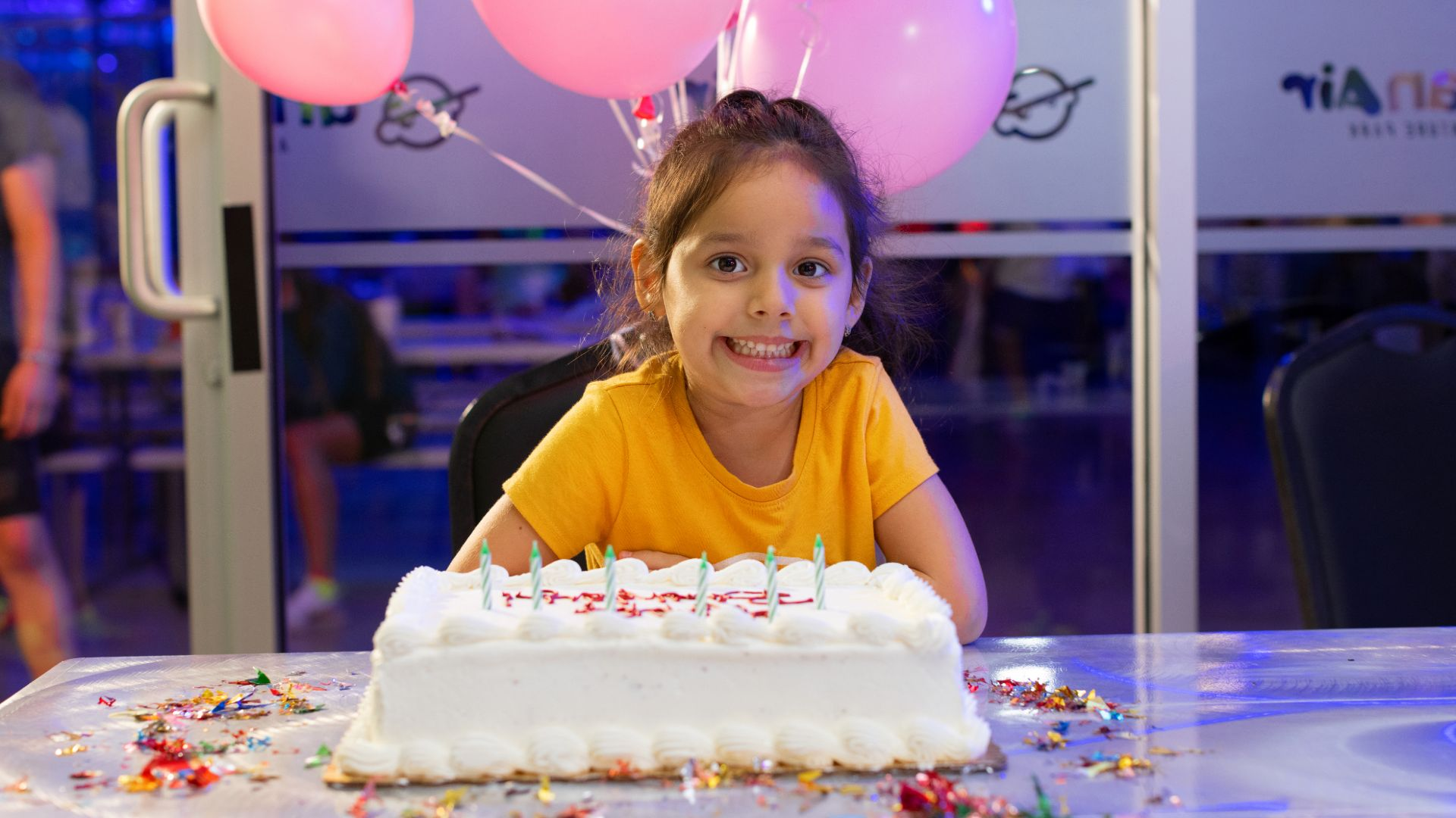 A young girl smiles in front of her Urban Air Birthday Cake