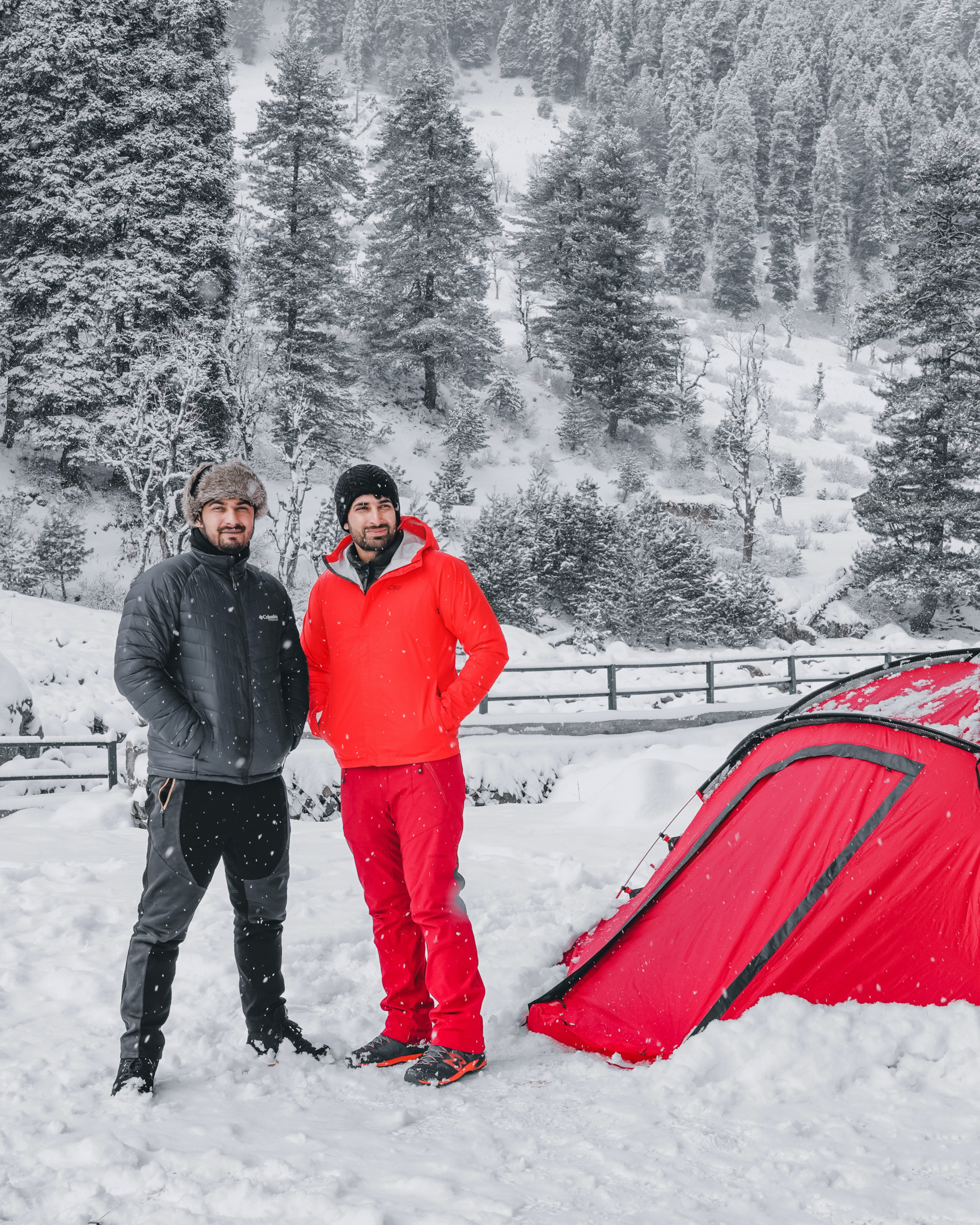 2 men standing in snow, red tent