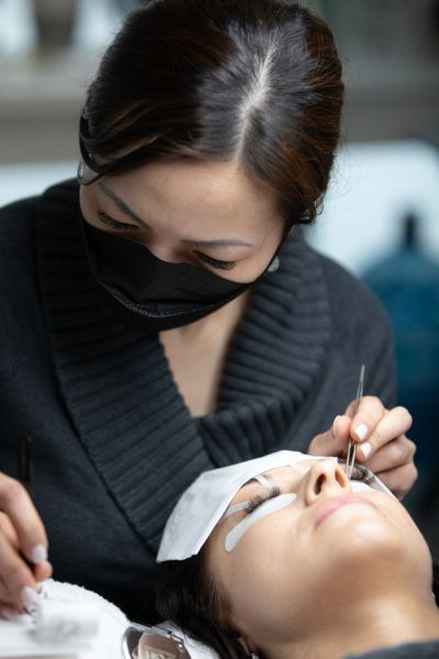 A woman receiving eyelash extensions during a touch-up appointment