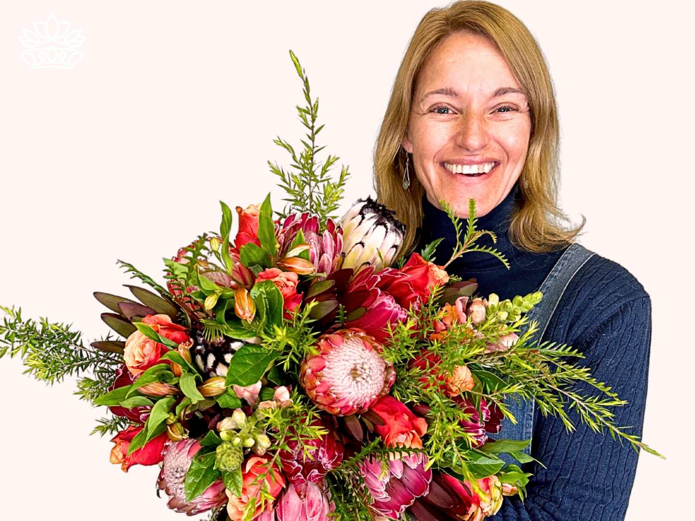 Joyful woman with a radiant smile, holding a classic range of florist-designed bouquets from the Florist Choice Bouquets Collection, featuring red proteas and pink lilies. Perfect for expressing support and affection to a sister or aunt. Fabulous Flowers and Gifts.