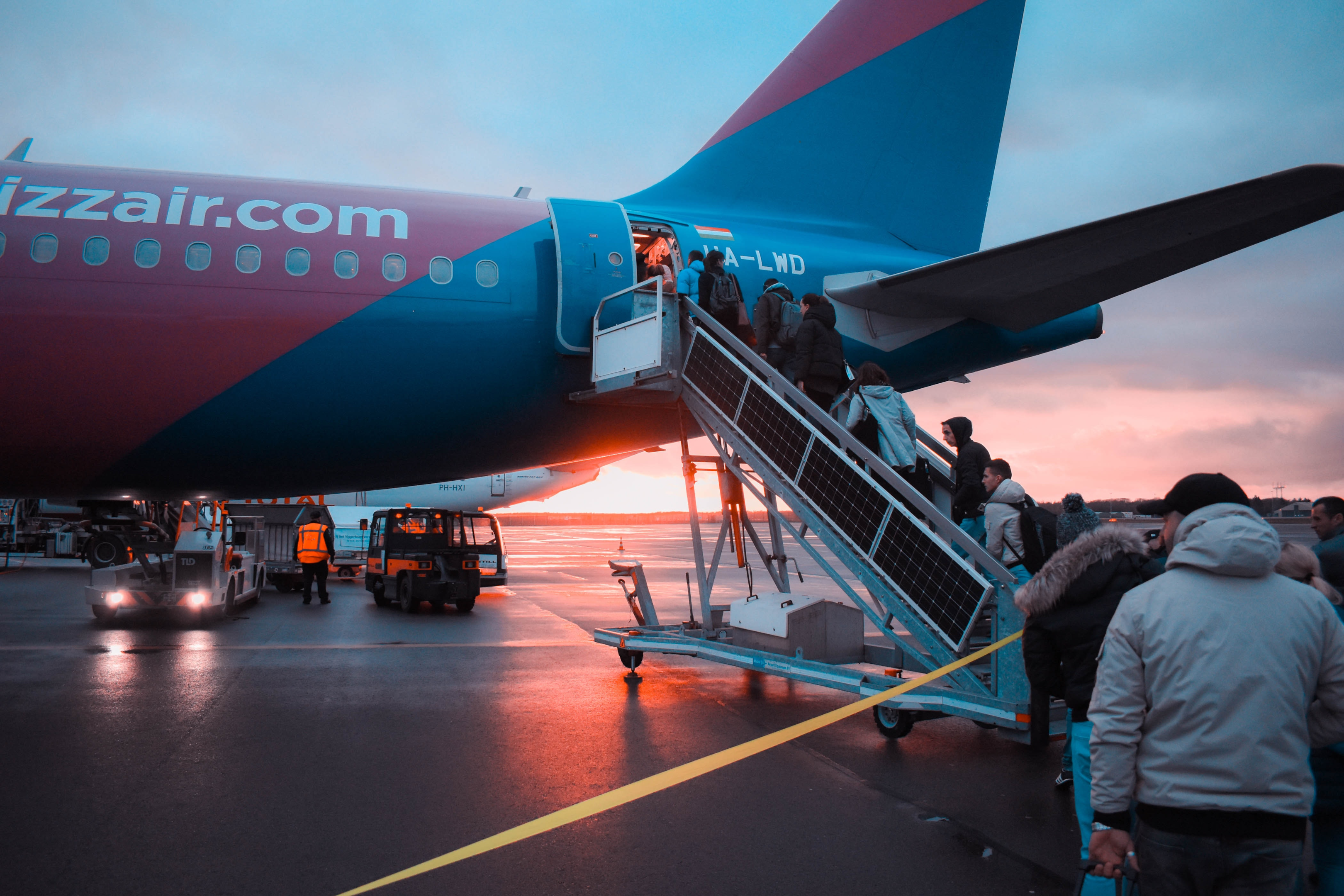 A line of travelers boarding an airplane while the sun is setting