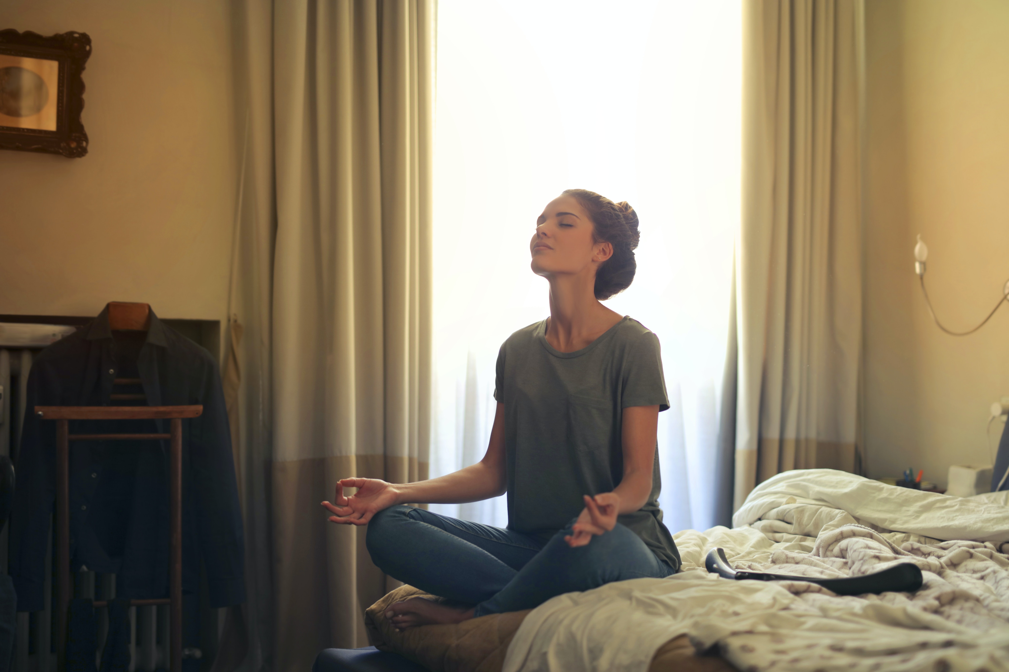 A woman sitting on the bed while practicing meditation techniques