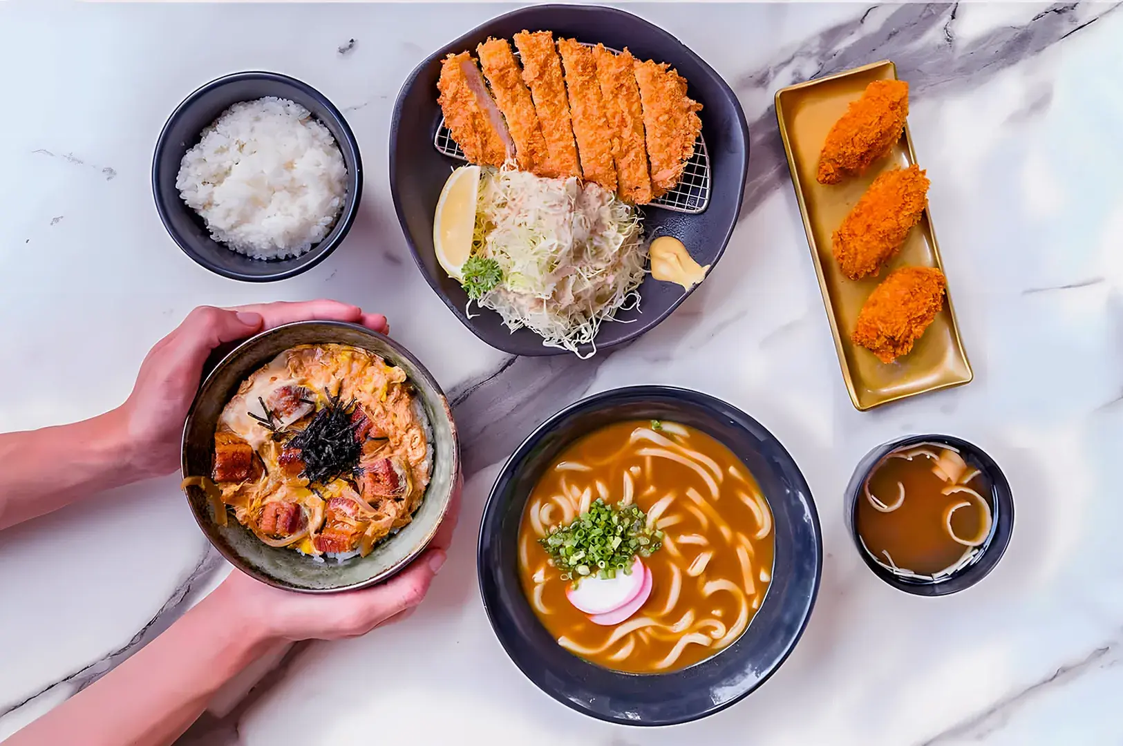 A plate of Japanese curry features crispy breaded shrimp, rice, and savory brown sauce, garnished with shredded cabbage and pickled ginger, conveying a warm, appetizing feel.
