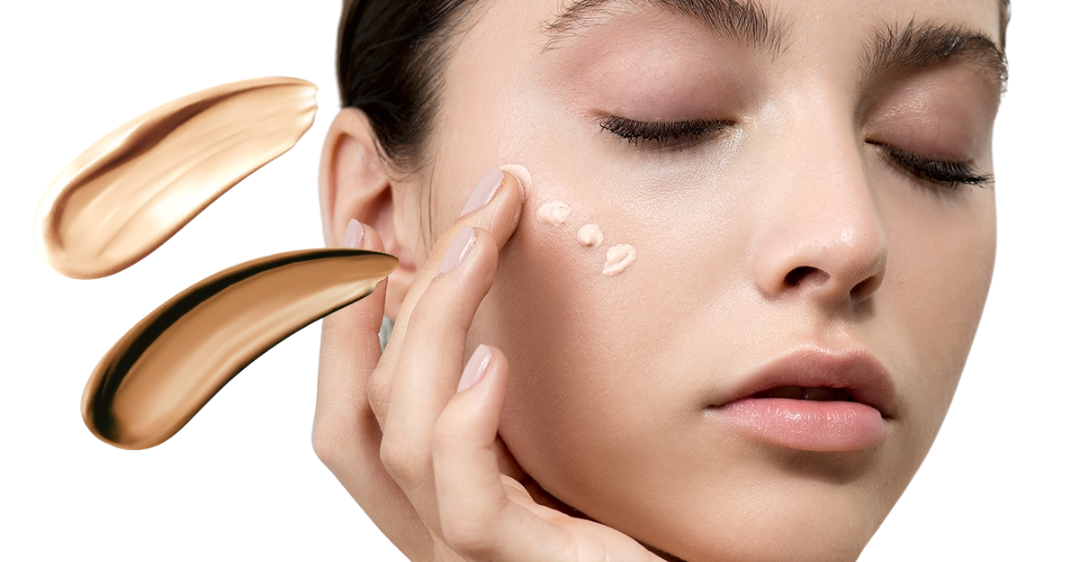 Vrouw brengt met haar vingers BB of CC cream aan op haar wang, met swatches van twee tinten foundation of getinte crème op de achtergrond.