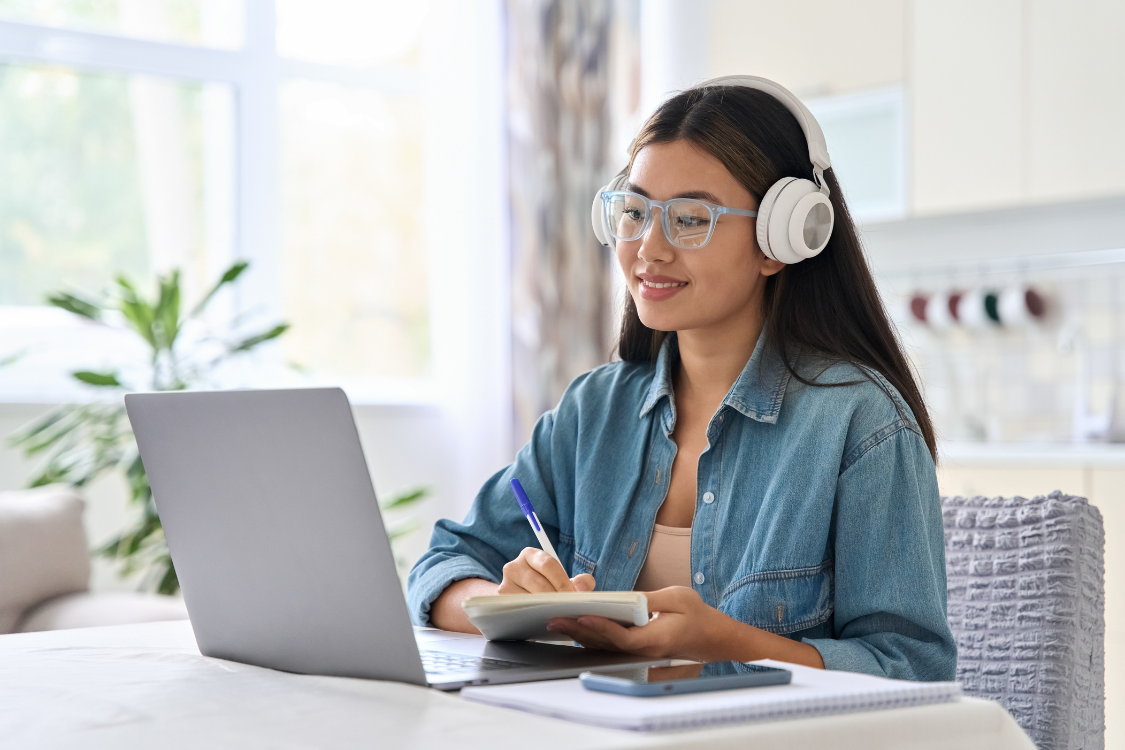 Filipino virtual assistant attending a remote onboarding session with headphones and notebook.