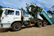 A Hook-lift truck unloading a hook Bin for commercial waste from warehouse 