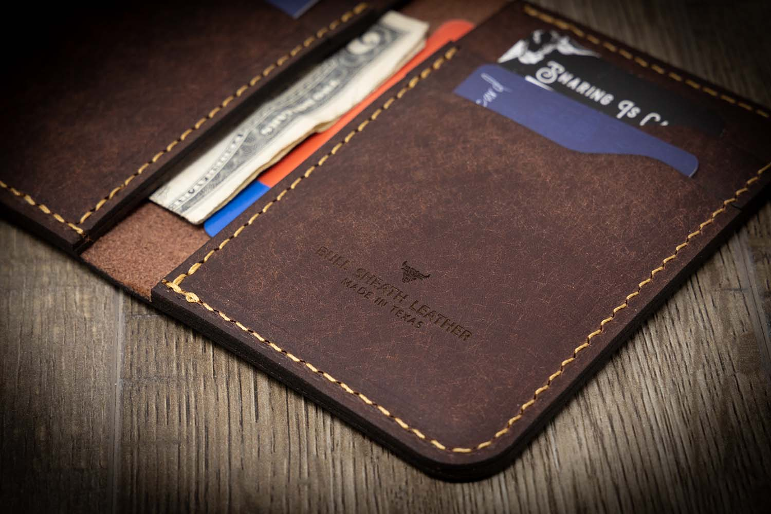 A close-up image of a bifold wallet front pocket made of genuine leather, with multiple card slots and a clear ID window.
