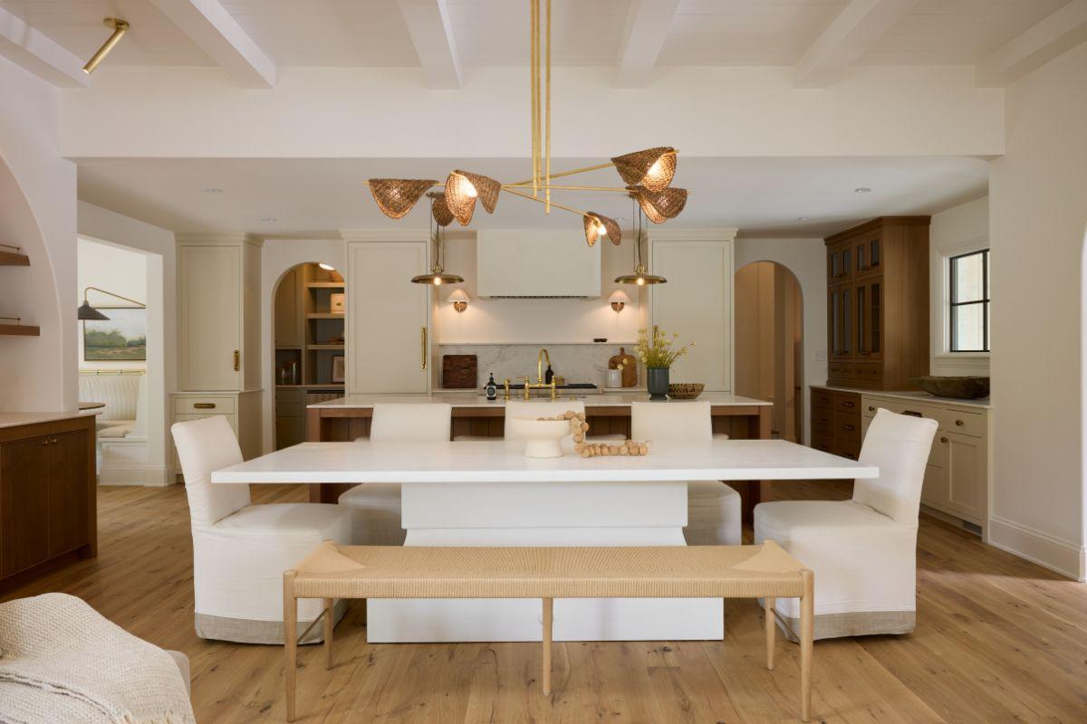 Modern dining area with a sculptural light fixture centred above a rectangular dining table, styled to reflect a warm and elegant personal preference