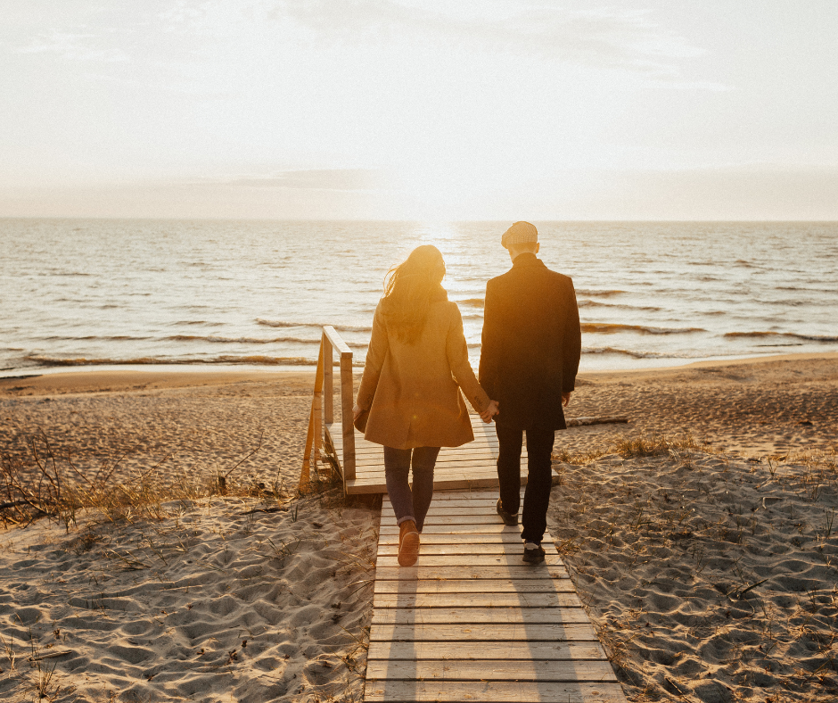 A couple holding hands and walking towards the sunset, representing the journey of how to get sober and stay sober in a healthy relationship.