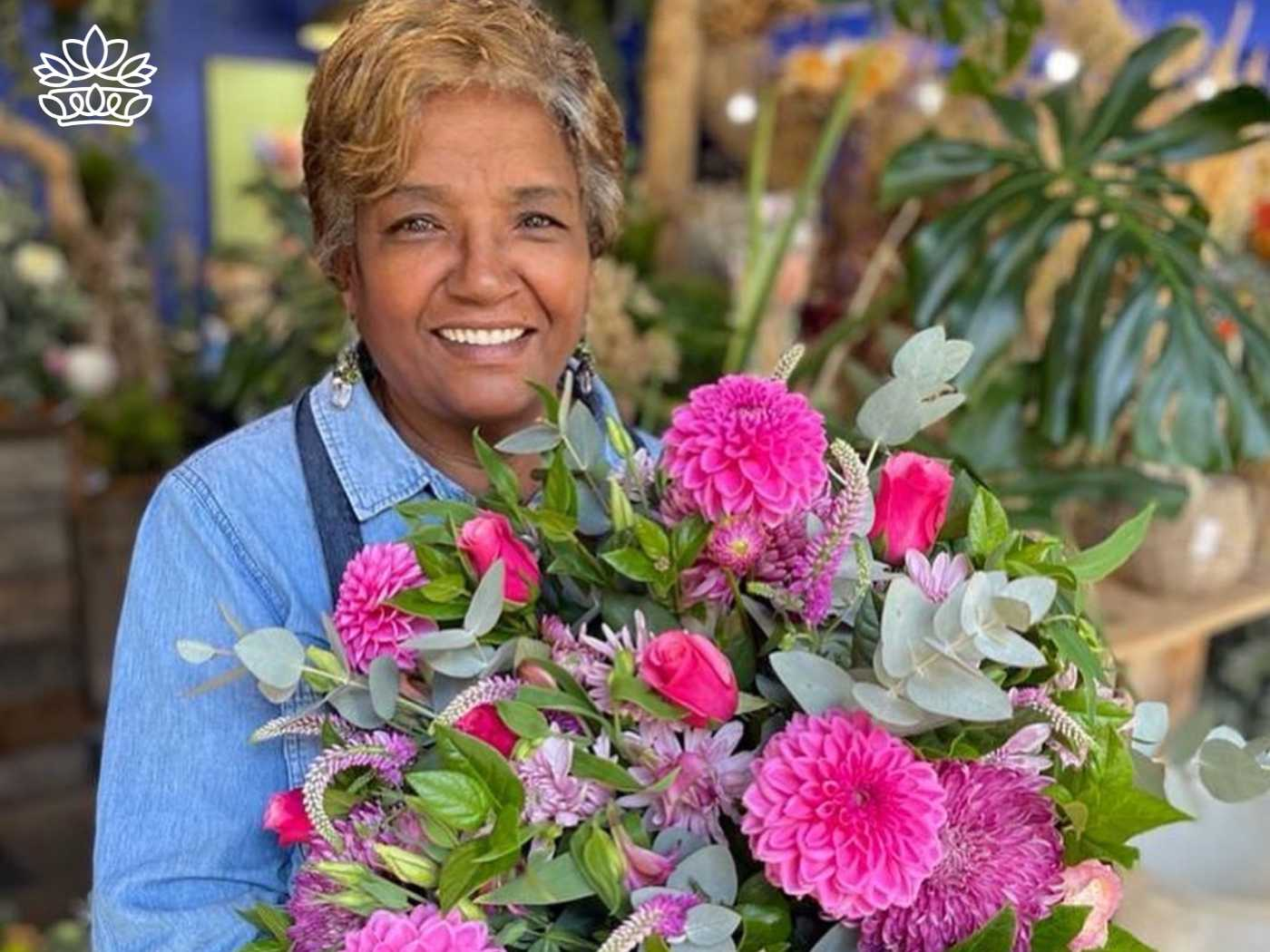 Smiling florist holding a colourful bouquet from the Flowers By Type Collection, featuring vibrant pink blooms in varying sizes, from Fabulous Flowers and Gifts. Perfect for brightening any page or growing your floral collection.