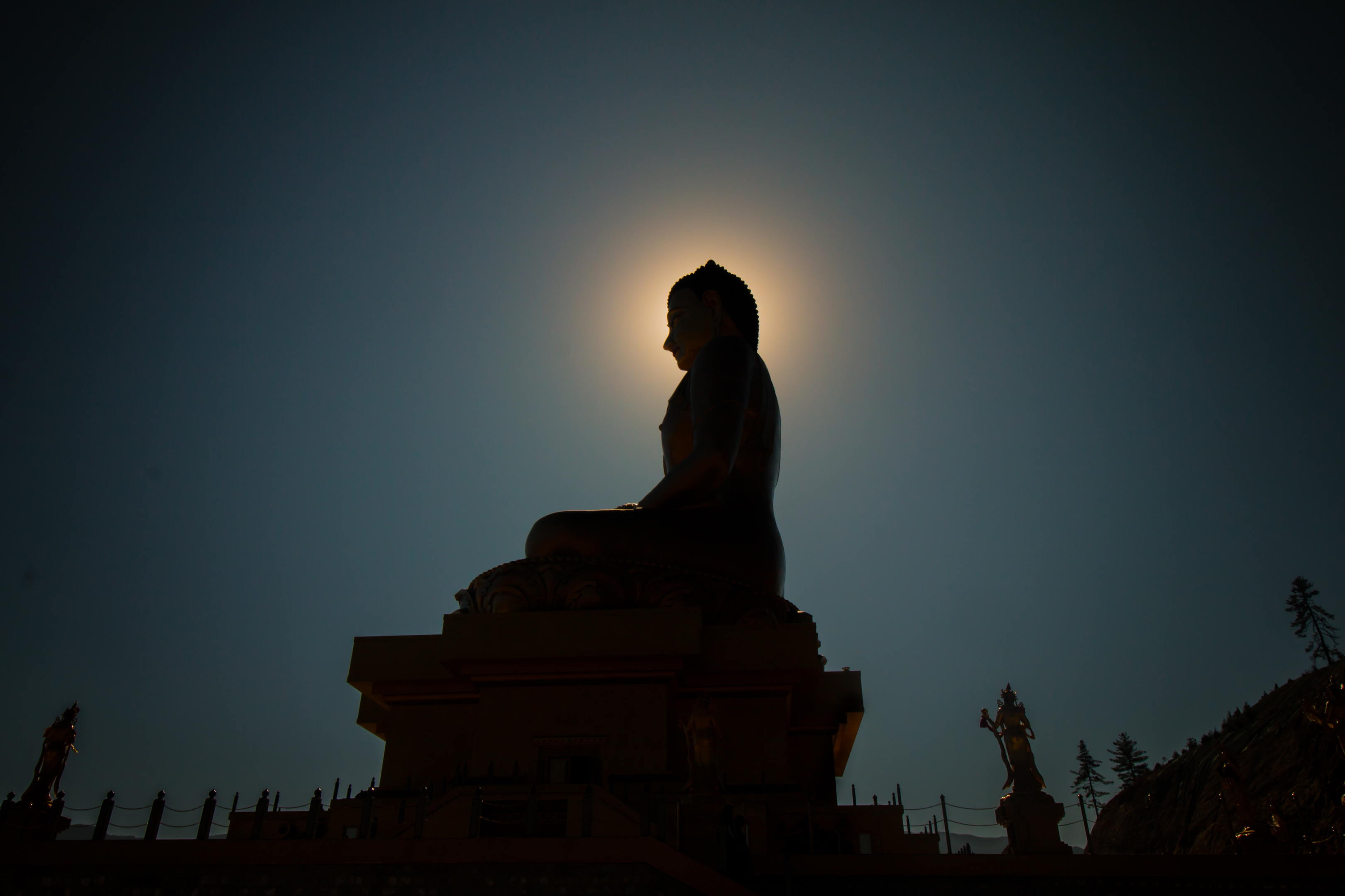 buddha statue silhouette at night with the moon behind his head