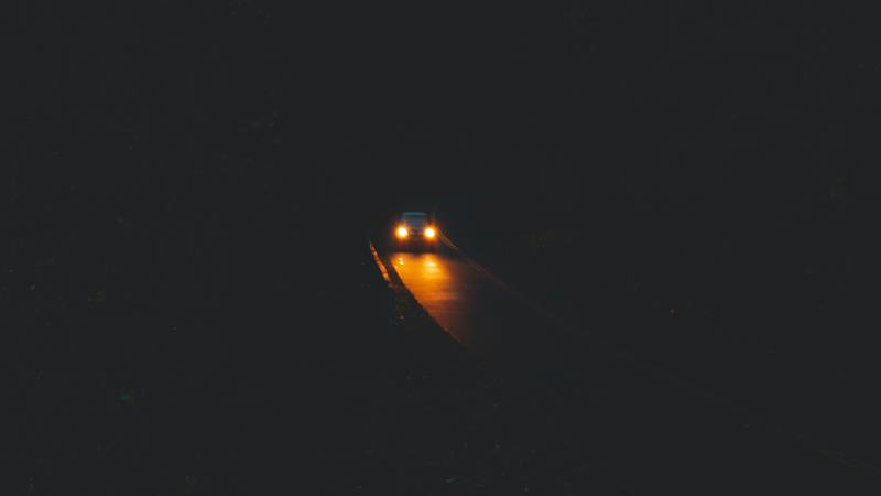 Car driving at night with yellow headlights.