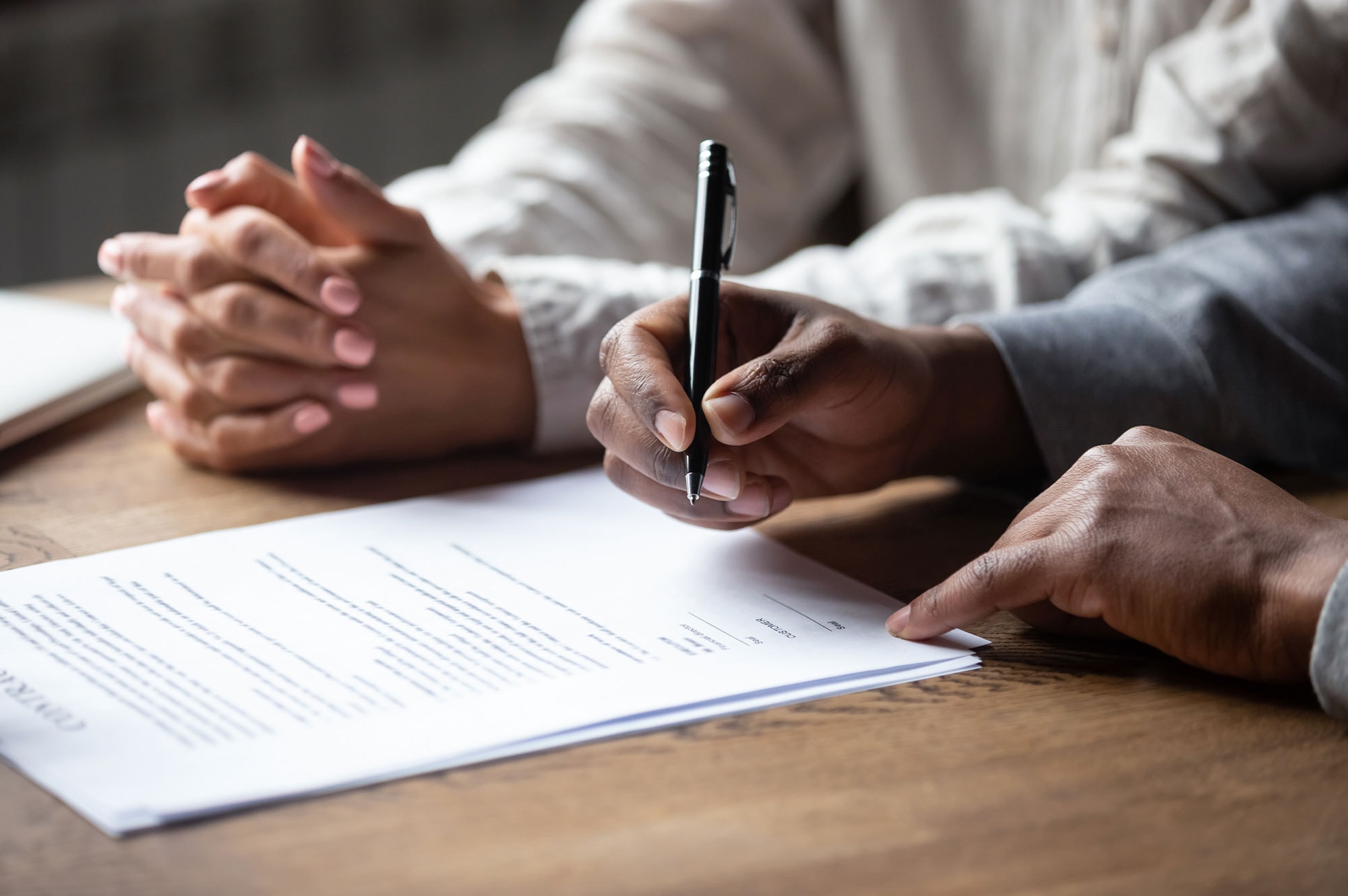 Close-up of hands signing a legal contract, highlighting the formal process of buying property through a trust