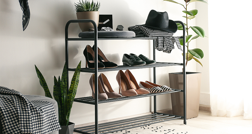 A shoe rack is the perfect solution for storing shoes and other essentials. This black four-tier shoe rack holds five pairs of shoes, while the top shelf is used to hold a hat, scarf, trinket tray and pot plant.