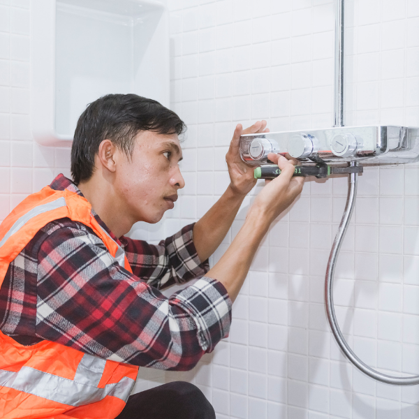 An image showing a plumber testing a repaired plumbing system.