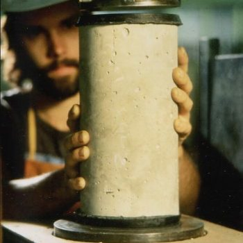 A person applying sulfur capping compound to a concrete test cylinder