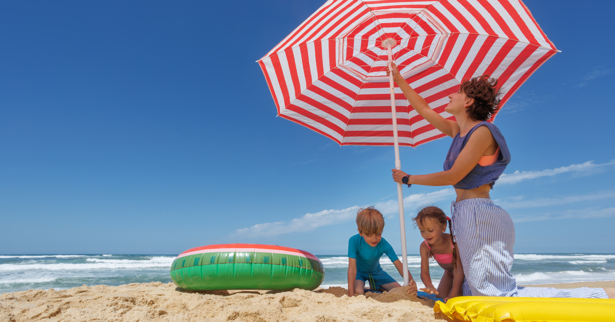Family enjoying a sunny summer day under a red and white umbrella on the beach in Cape May Point, New Jersey.