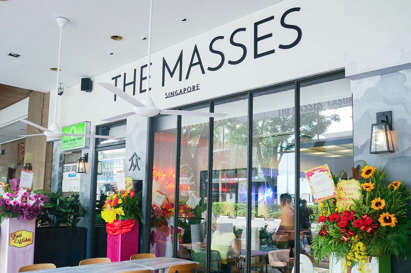 The Masses Singapore restaurant exterior decorated with vibrant flower stands.