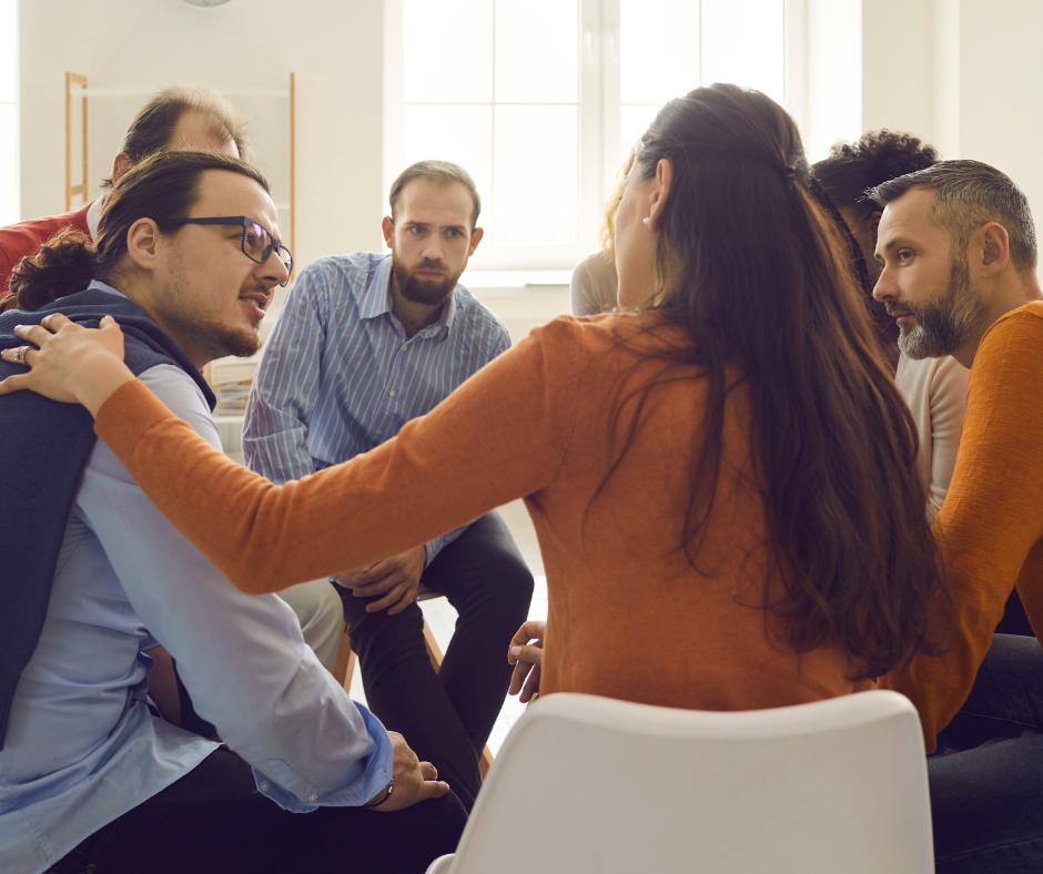 A group of people in a drug rehab facility discussing their treatment programs