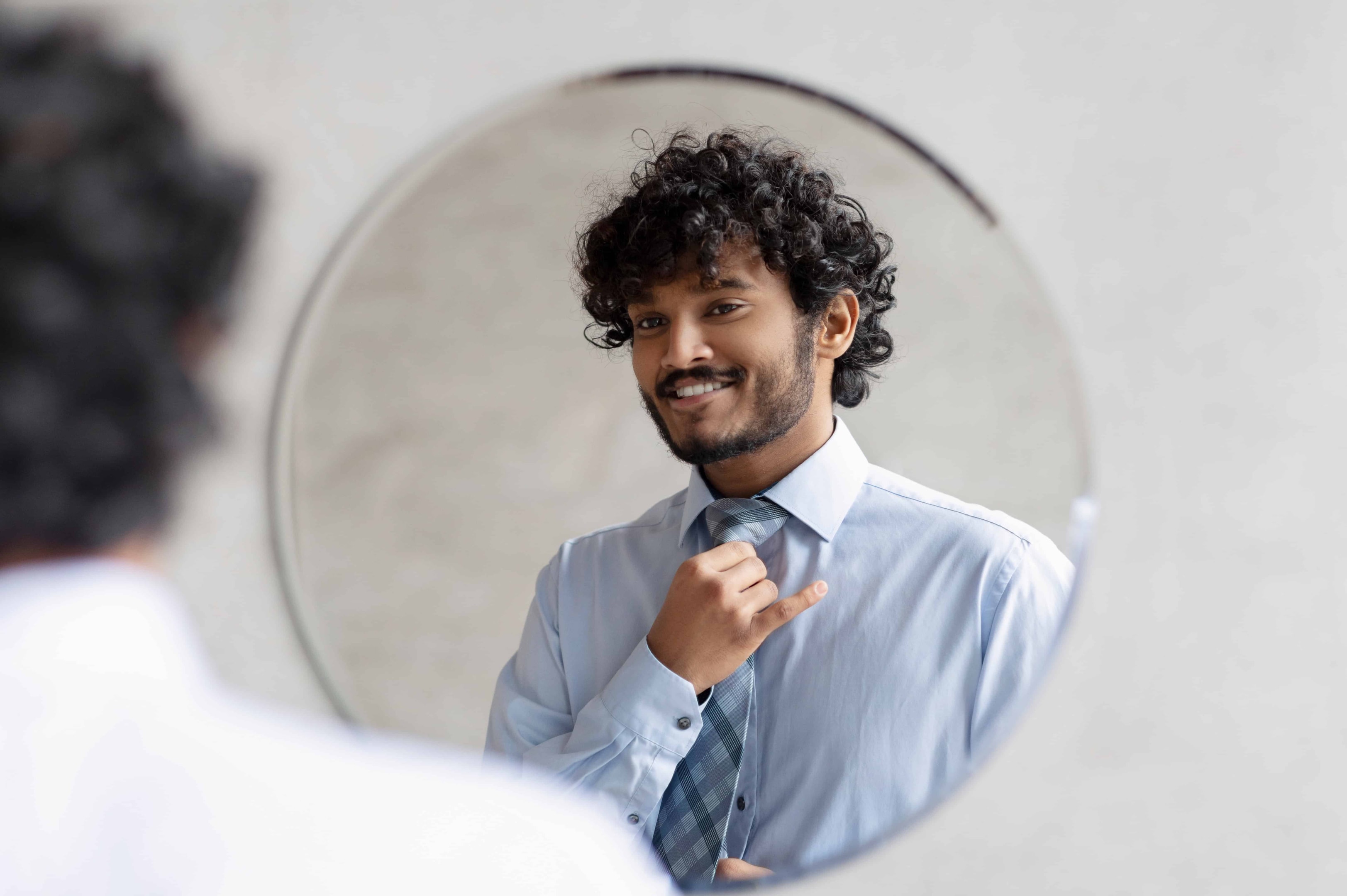 A man looking in the mirror trying to practice self love by looking in the mirror and using affirmations.