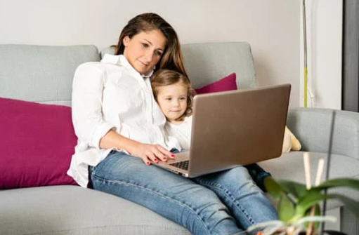 Mum sitting on sofa with her daughter and laptop