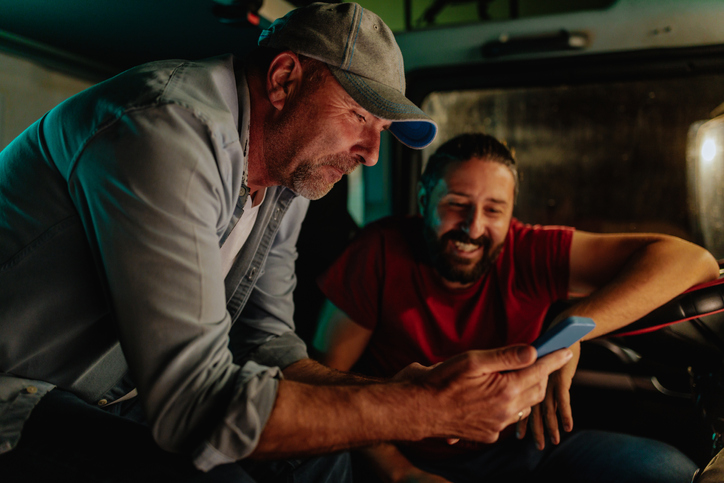 Two adult men researching something on a cell phone. 