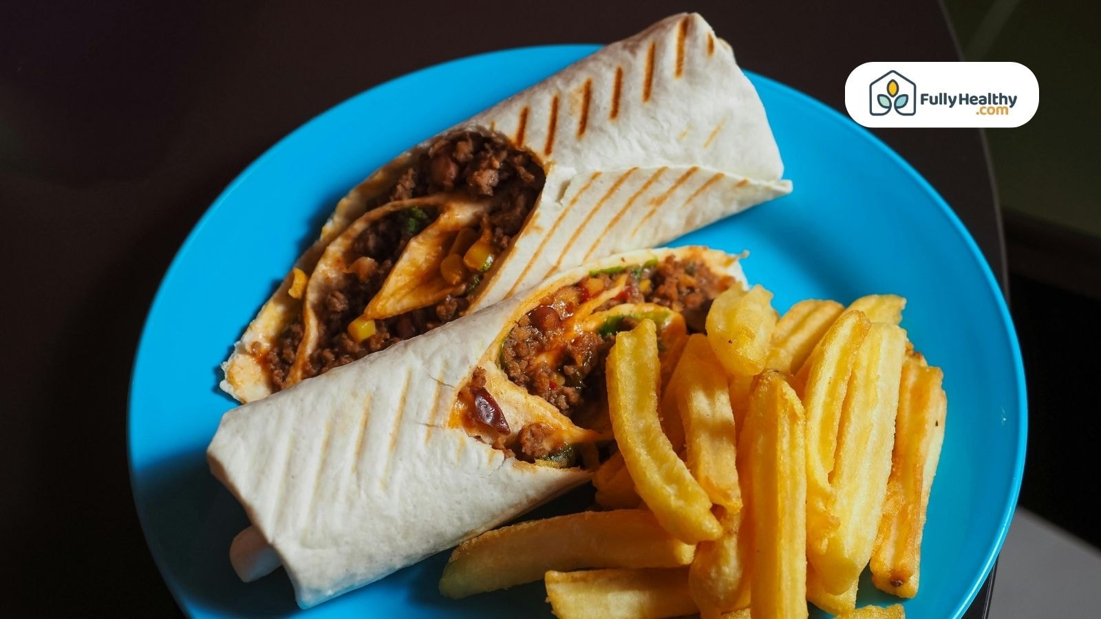 Grilled wrap with beef, vegetables, and fries on a blue plate