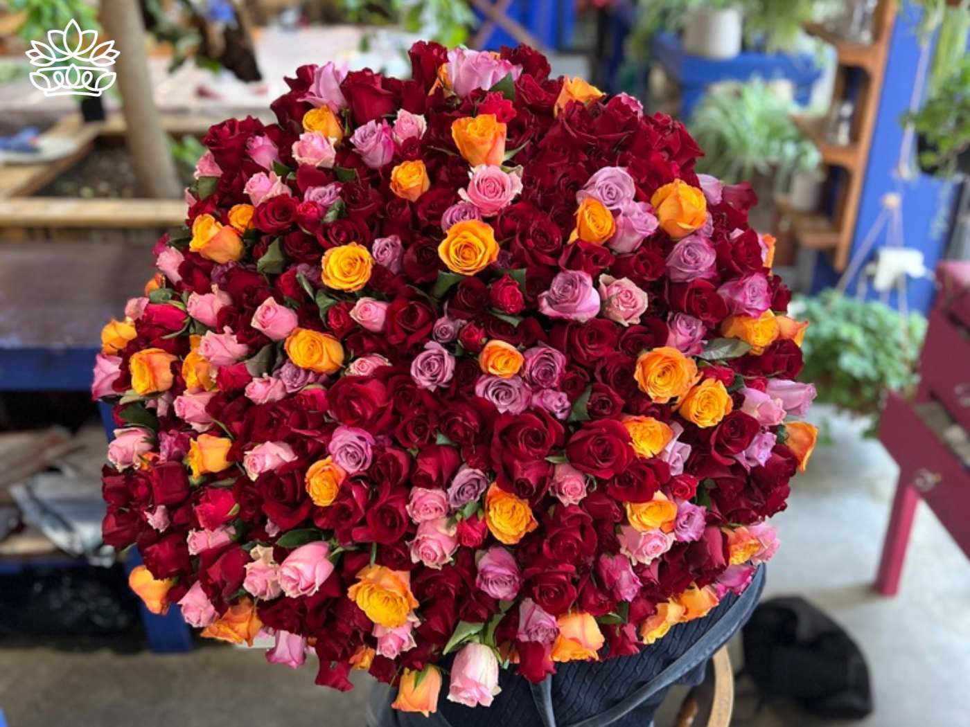 An exquisite close-up view of a large bouquet composed of tightly packed multicoloured roses ranging from deep reds to vibrant oranges and pinks, part of the Flowers By Occasion Collection at Fabulous Flowers and Gifts.