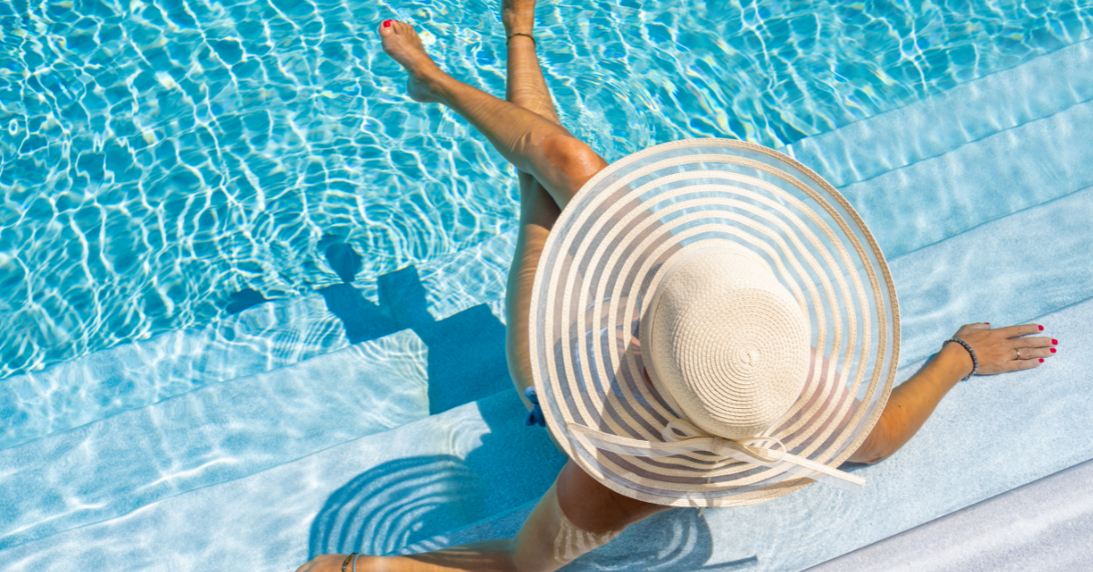 Woman relaxing in a pool with a sunhat at an Ocean Grove vacation rental, perfect for summer getaways near the beach.