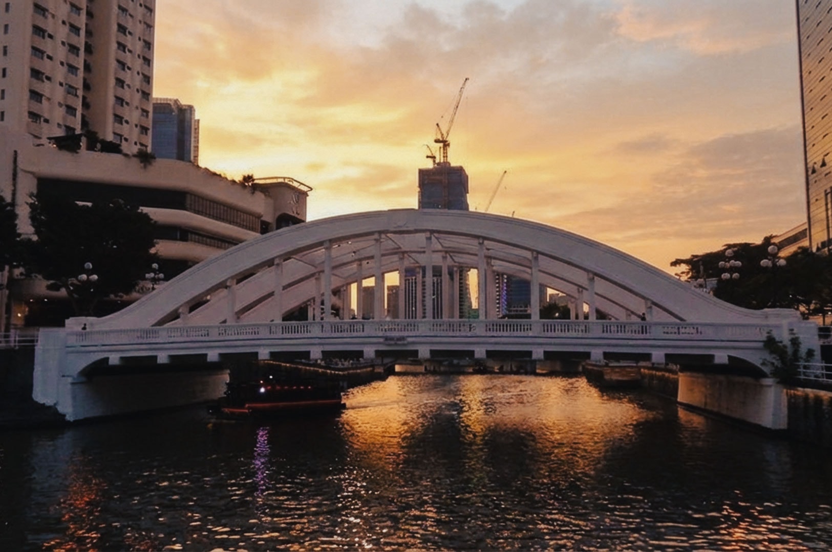 Elgin Bridge over the Singapore River glowing under a vibrant sunrise sky.
