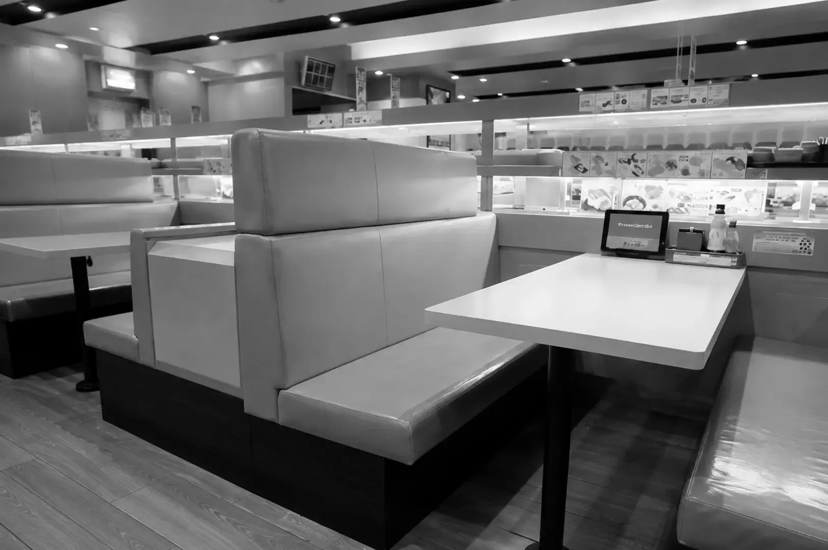 Modern conveyor belt sushi restaurant with booth seating and bright interior lighting.