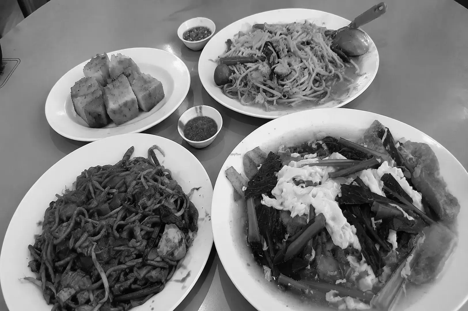 A shared table of diverse vegetarian dishes including noodles, vegetables, and plant-based meals.