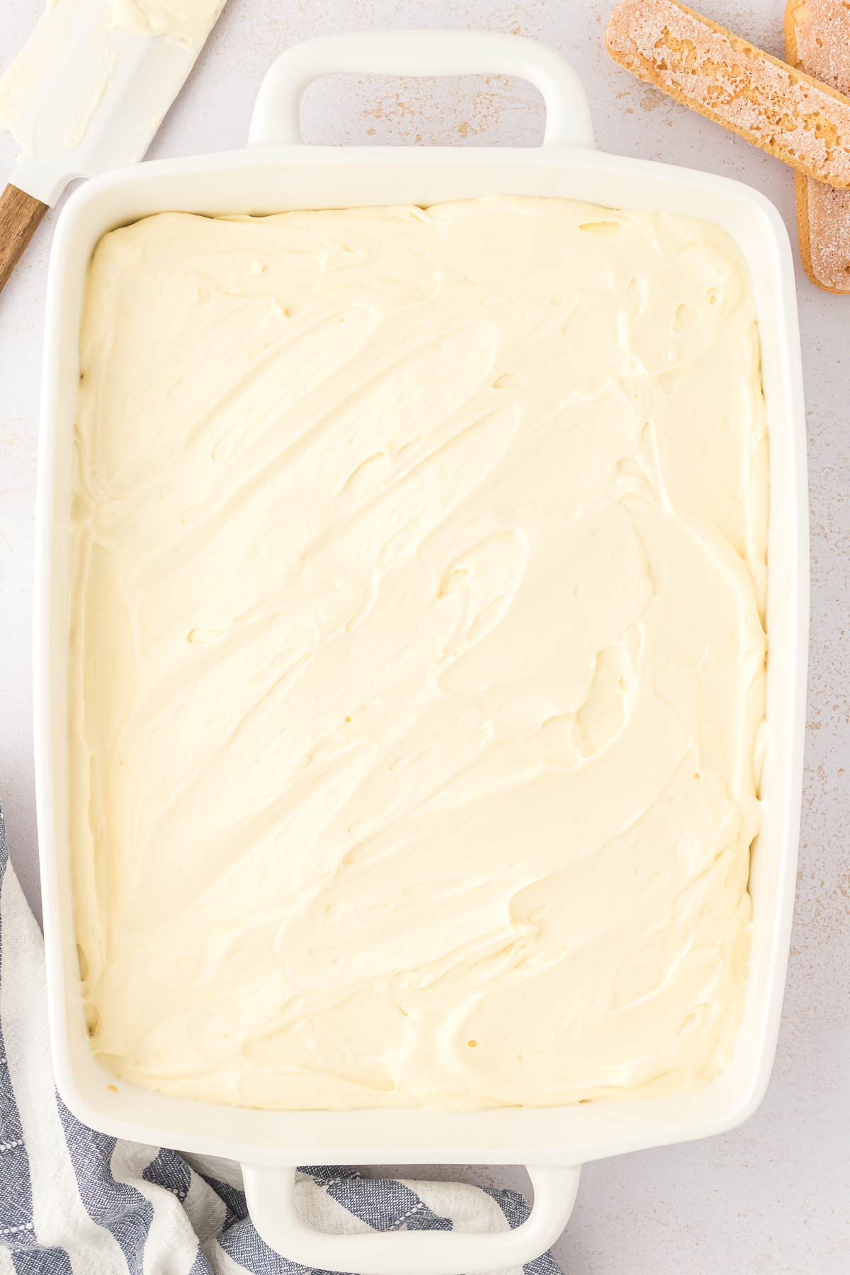 mascarpone mixture spread on top of ladyfingers in baking dish