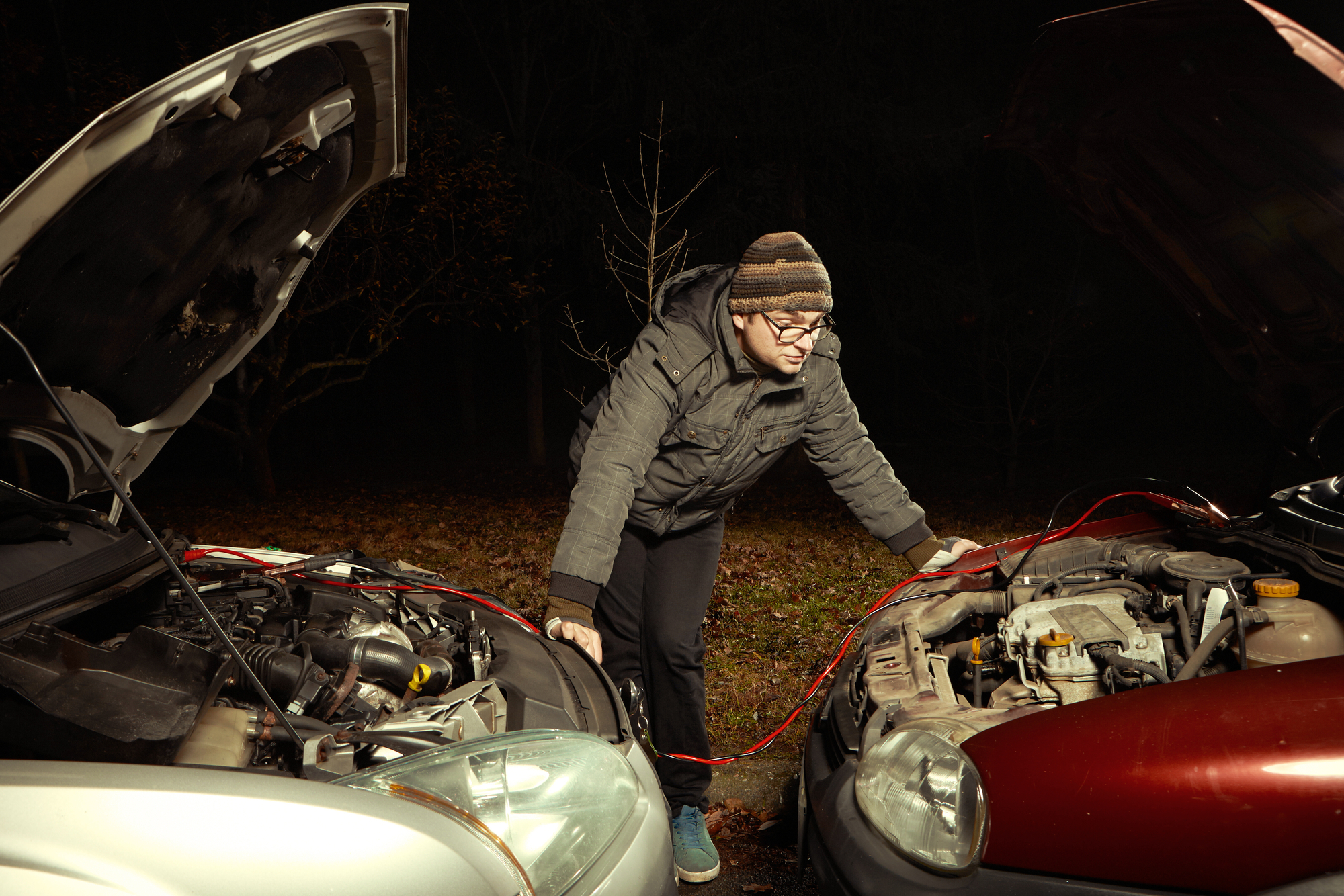 Man jump starting his car at night.