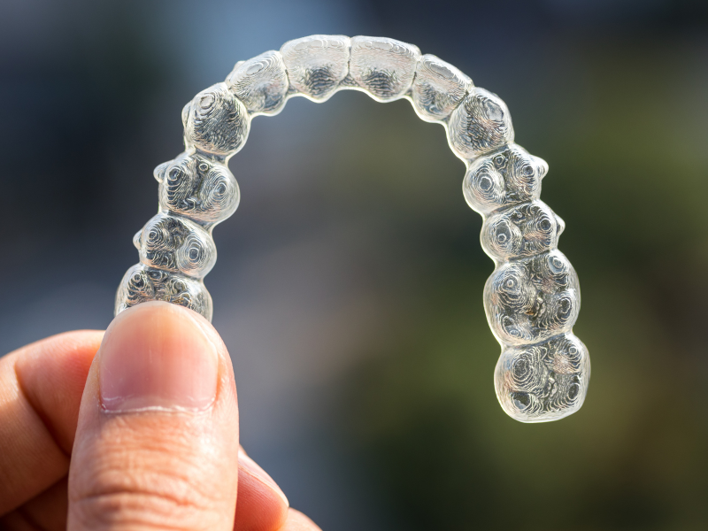 Image of someone holding up a clear aligner.