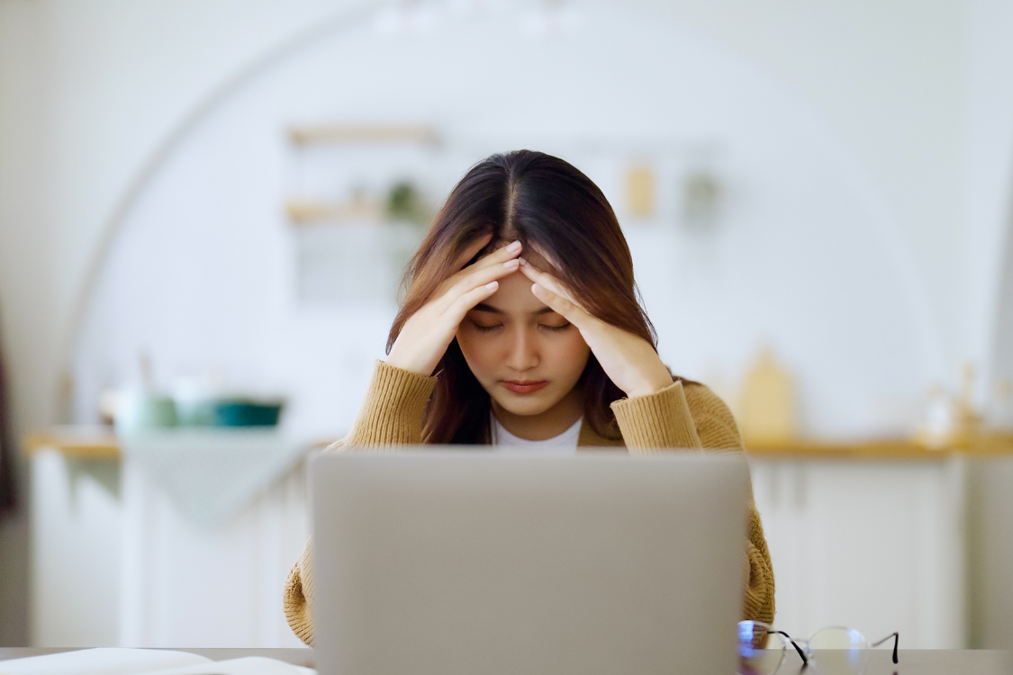 A stressed Filipino remote worker holding her head during a tough day
