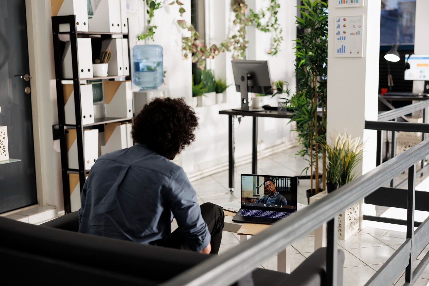 A professional working remotely in a well-lit, modern office lounge, attending a virtual meeting on a laptop. This scene exemplifies Business VoIP providers enabling flexible, high-quality Cloud communications.