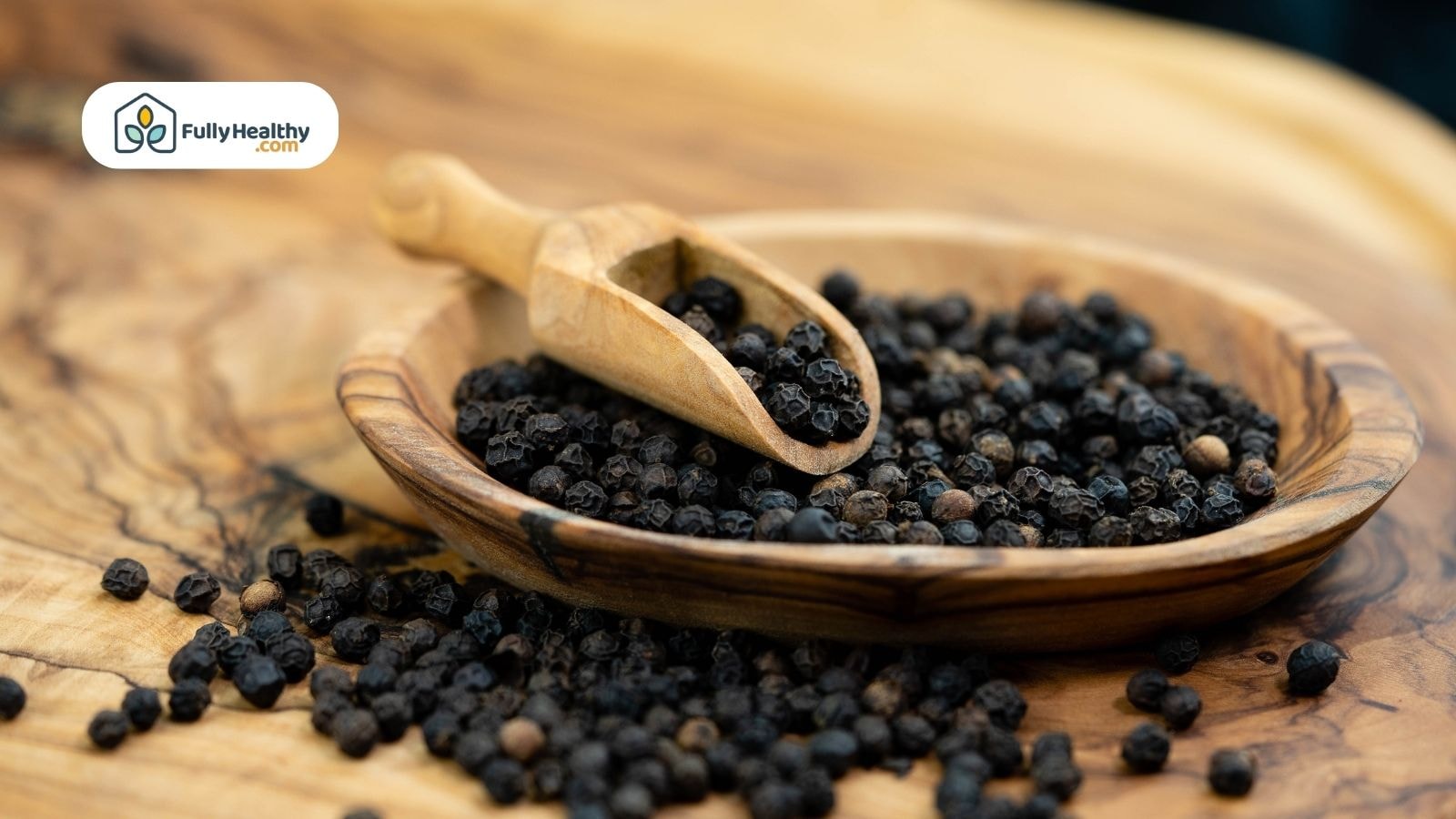 Black peppercorns in wooden bowl with scoop on rustic surface