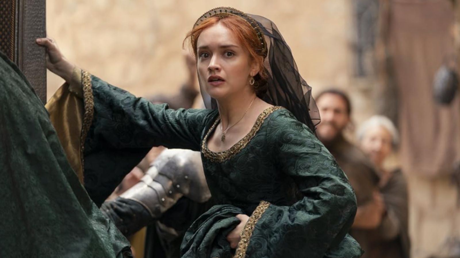 Olivia Cooke as Queen Alicent Hightower in green gown hurries through crowded street in House of the Dragon Season 2