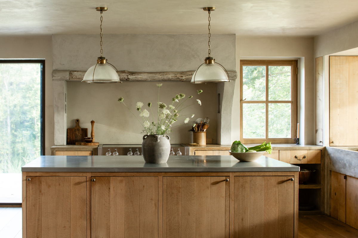Two pendant light fixtures with brass details over a rustic kitchen island, adding warmth and simple illumination to the room.