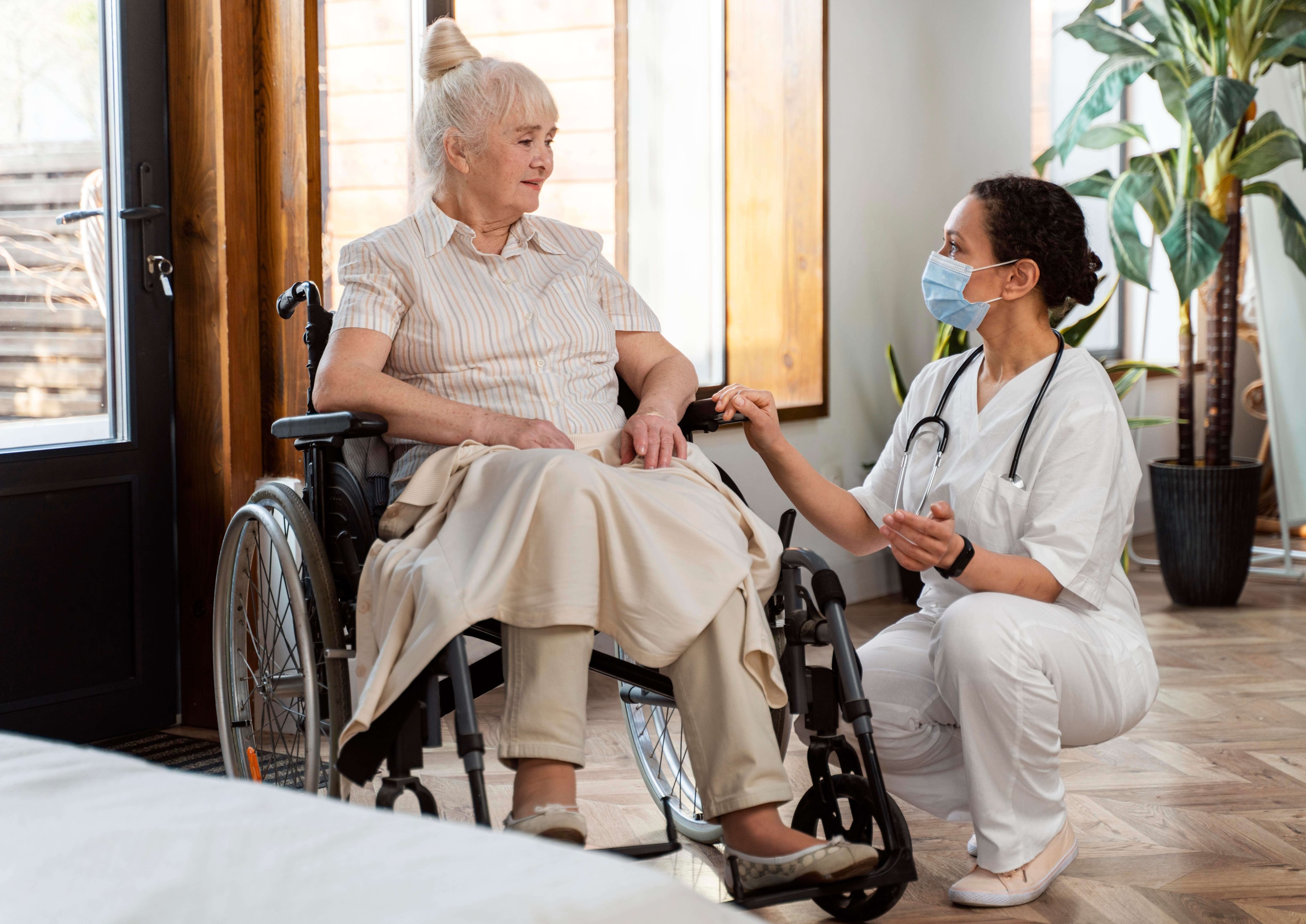 woman in wheelchair living in a nursing home facility being taken care by staff