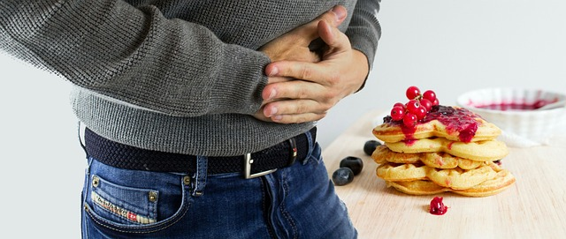 An image of a man with common food allergies holding his stomach in pain. 