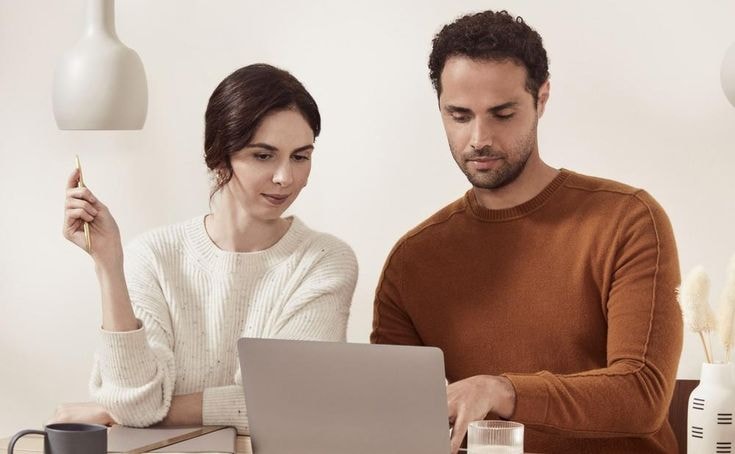 Mężczyzna i kobieta patrzą w ekran laptopa podczas pracy w domu.
