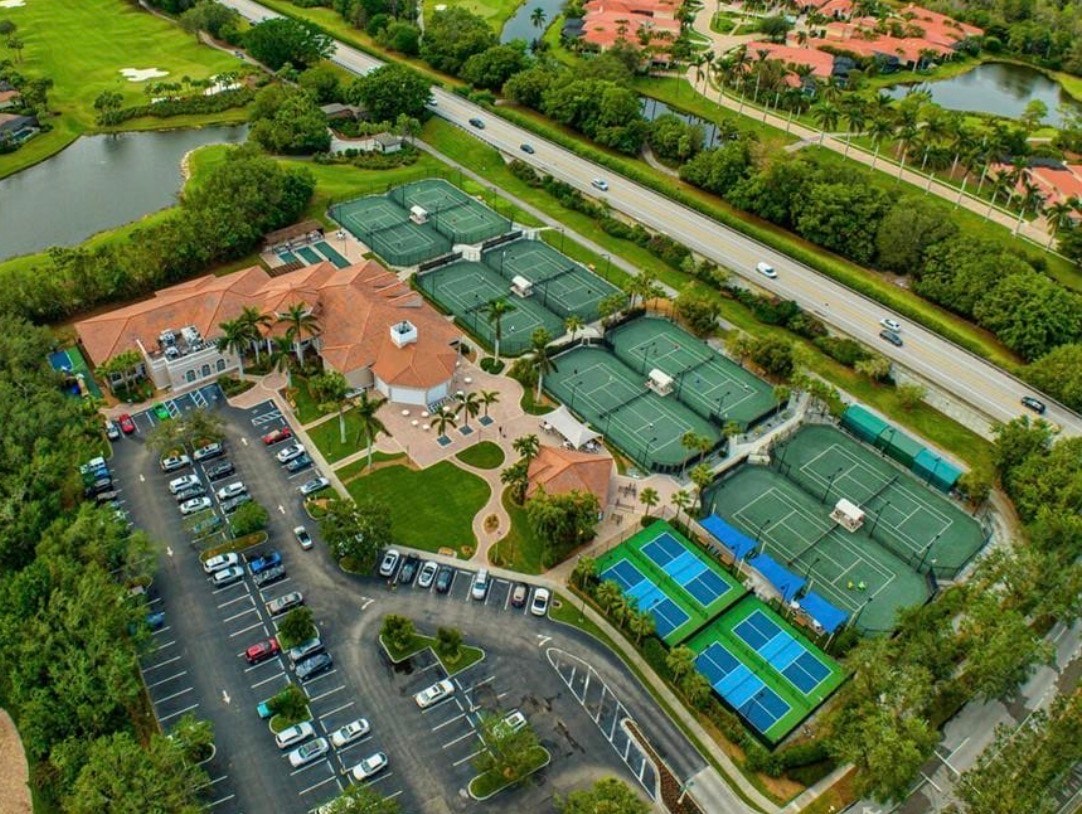 An aerial view of the Pelican Marsh gated community in Naples, Florida, showcases the lush landscaping, luxury homes, and well-maintained golf courses, including the Pelican Marsh Golf Club. The image highlights the community's amenities, such as tennis courts and a community pool, set against the backdrop of Vanderbilt Beach Road.