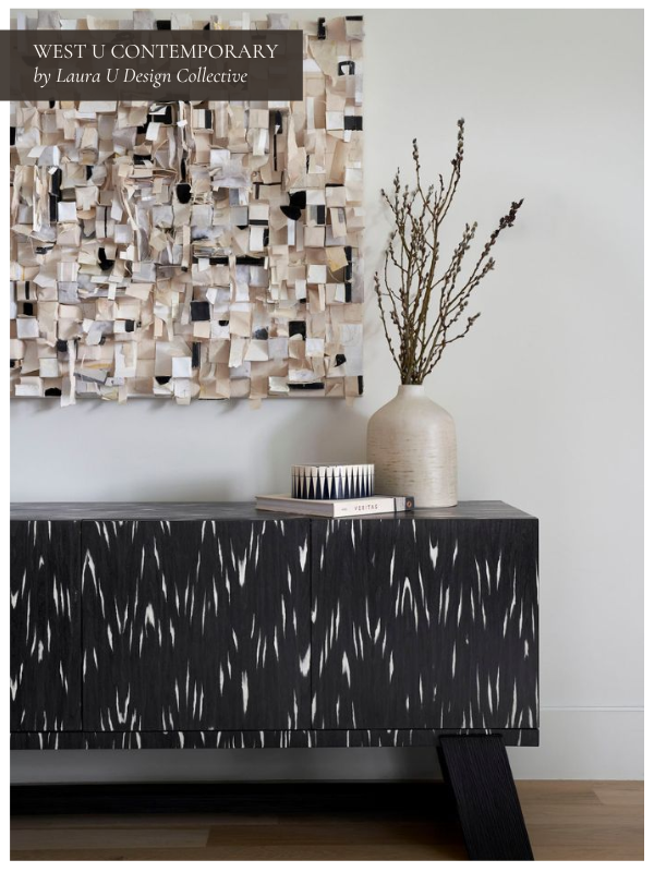 A modern entryway with a black and white patterned console, neutral walls, a sculptural wall art piece with layered materials, and a ceramic vase with branches.