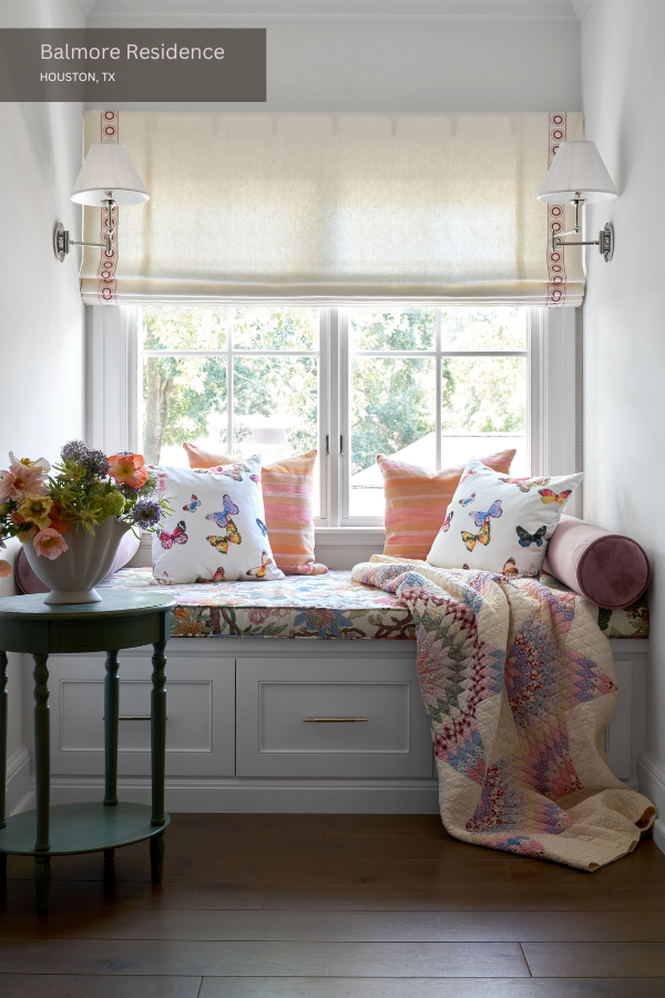 A reading nook with two sconces, butterfly-patterned pillows, and a window seat