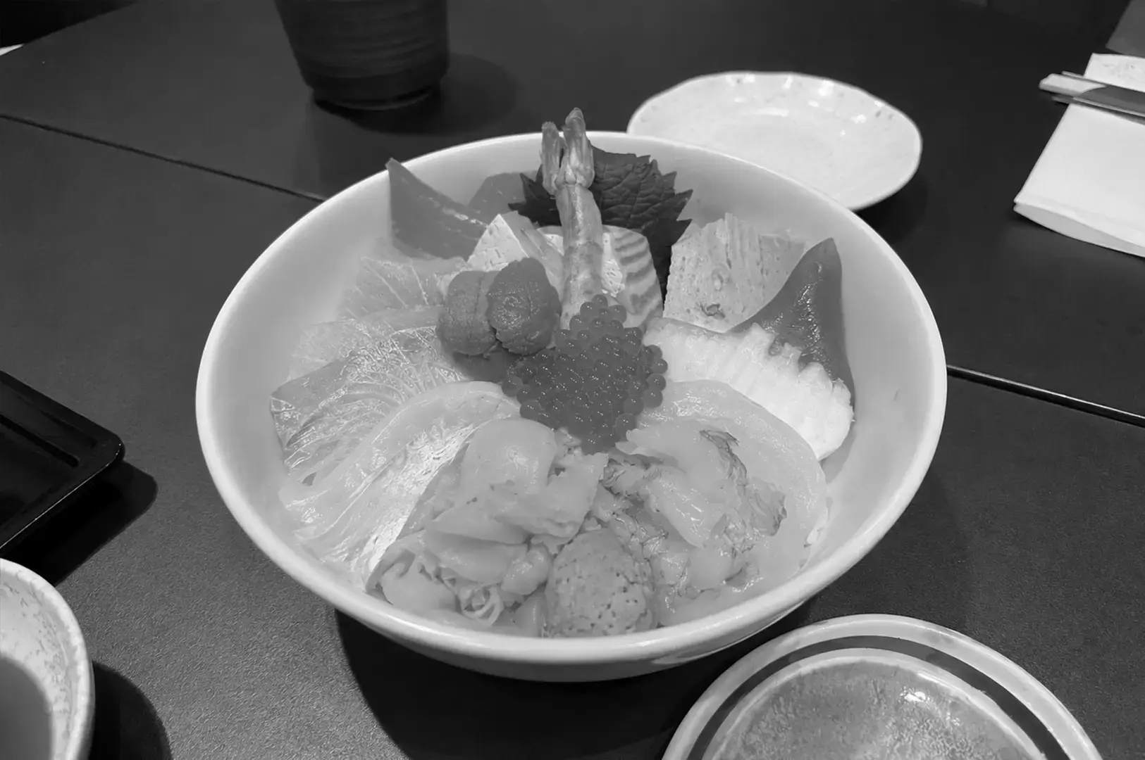 Standing Sushi Bar chirashi don with salmon, white fish, scallops, ikura, uni, and assorted sashimi over rice.