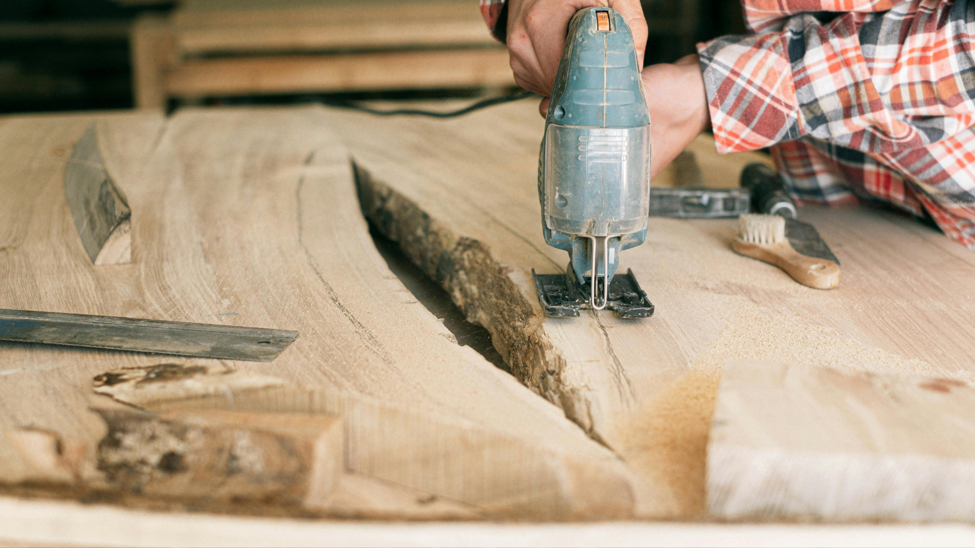 A person using a skill saw to cut around a hole in a live-edge piece of lumber.
