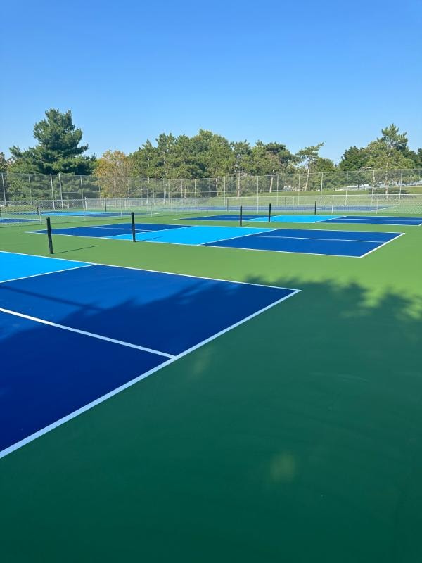 Multi-sport court at Memorial City Park in Arcadia, WI, featuring a smooth acrylic surface and clear striping for both tennis and pickleball after repairs and resurfacing.