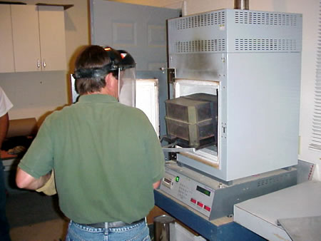 A technician preparing an asphalt sample for testing in an ignition oven